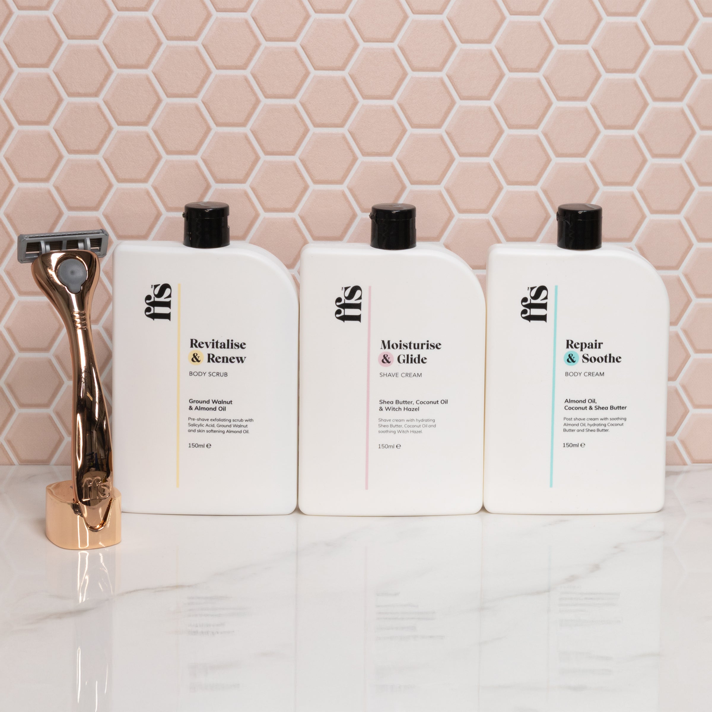FFS Body Scrub, Shave Cream and Body Cream bottles lined up with a rose gold razor against pink hexagonal tiles